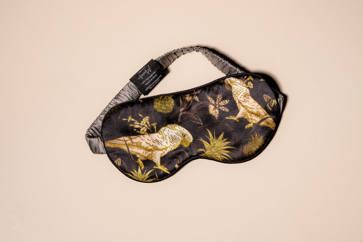 Sleep mask with gold bird design on a beige background